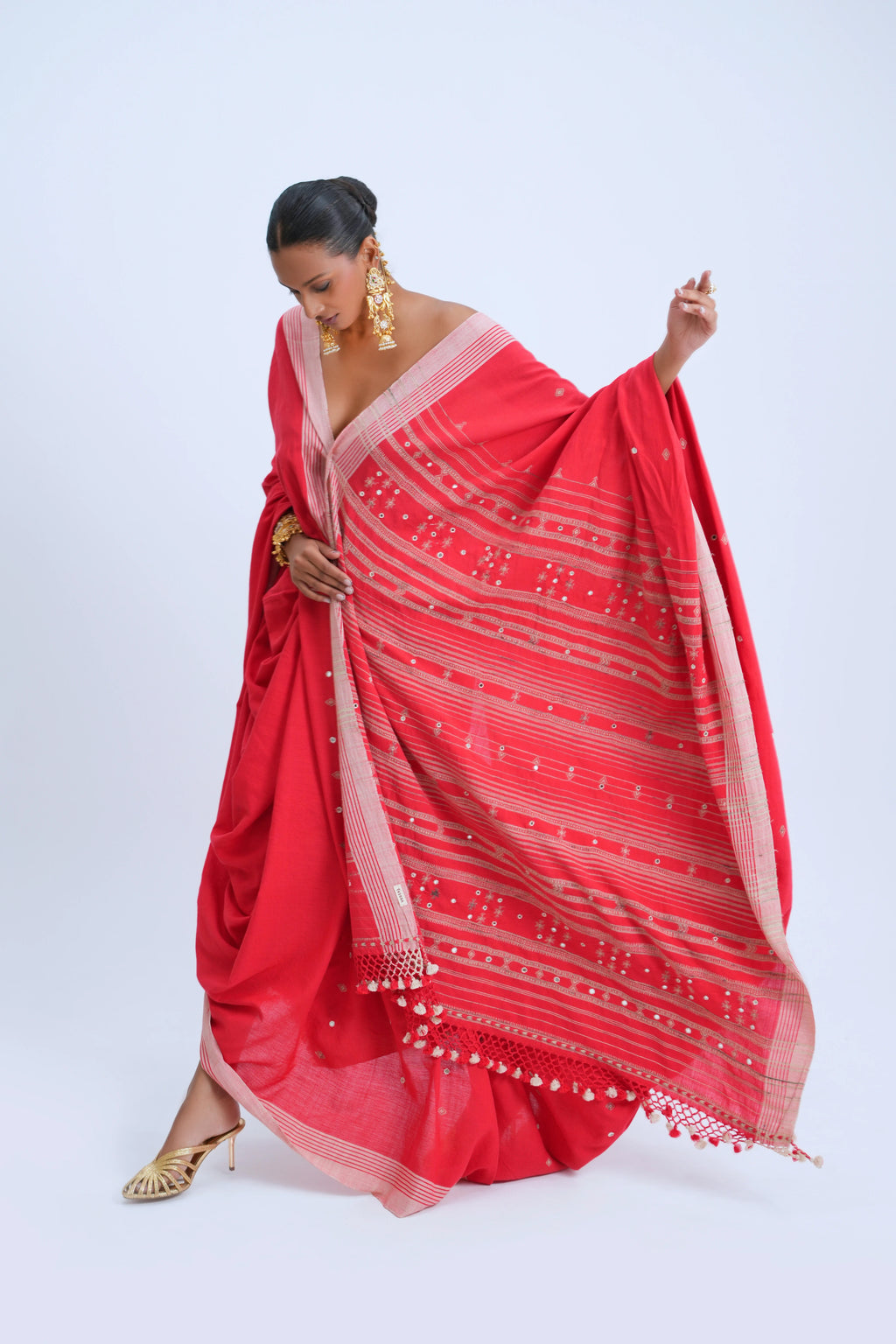 Studio action shot highlighting the fluid drape, vibrant scarlet hue, and detailed golden pallu of the Bhujodi saree
