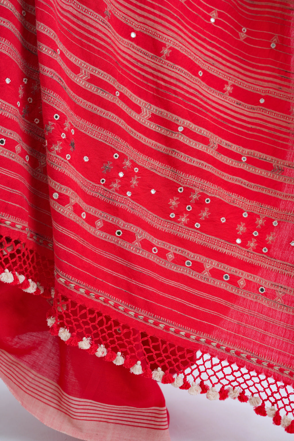 Close-up view of the dense golden-ivory horizontal stripe pallu embellished with hand-embroidered mirror work and delicate tassel fringe
