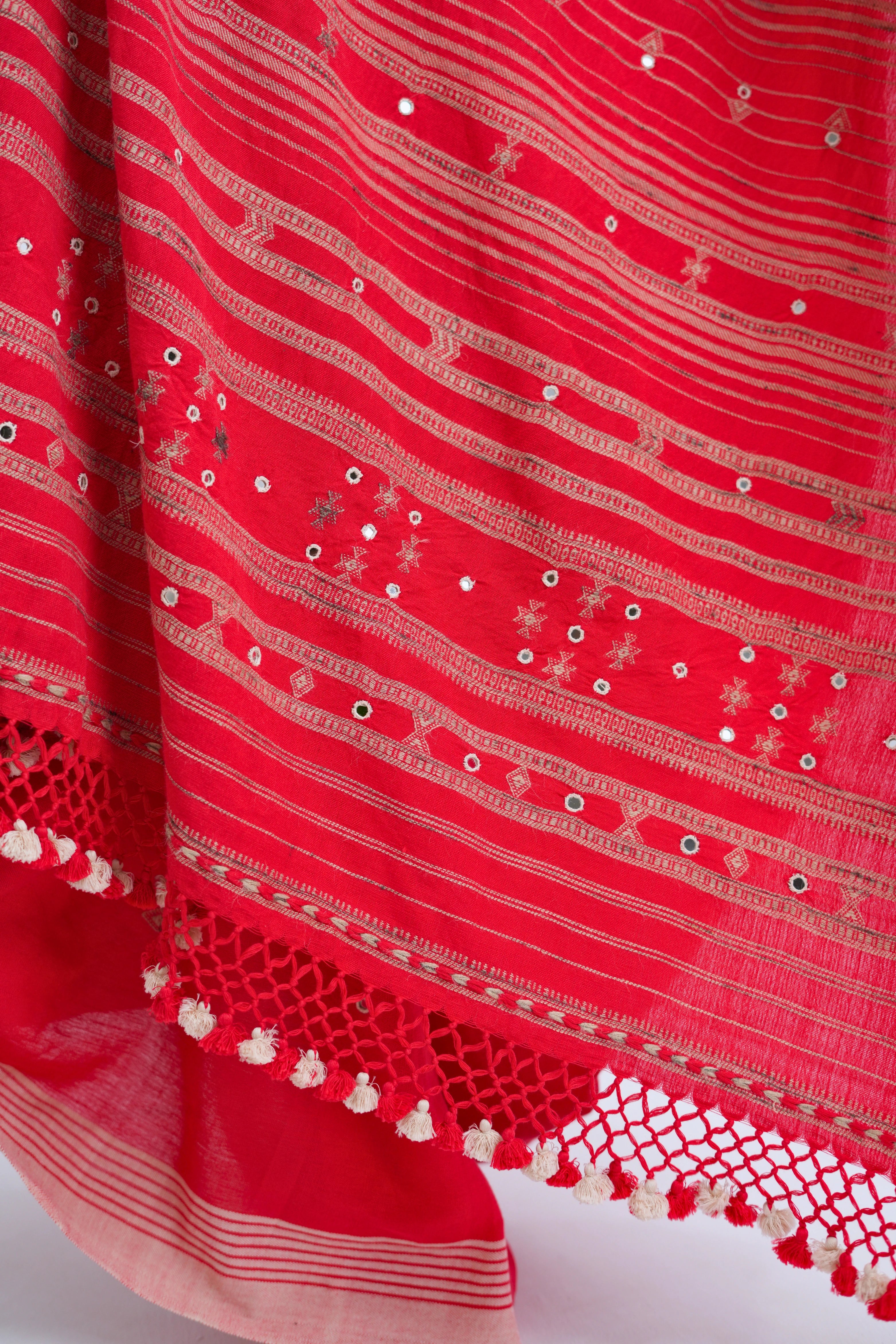 Close-up view of the dense golden-ivory horizontal stripe pallu embellished with hand-embroidered mirror work and delicate tassel fringe