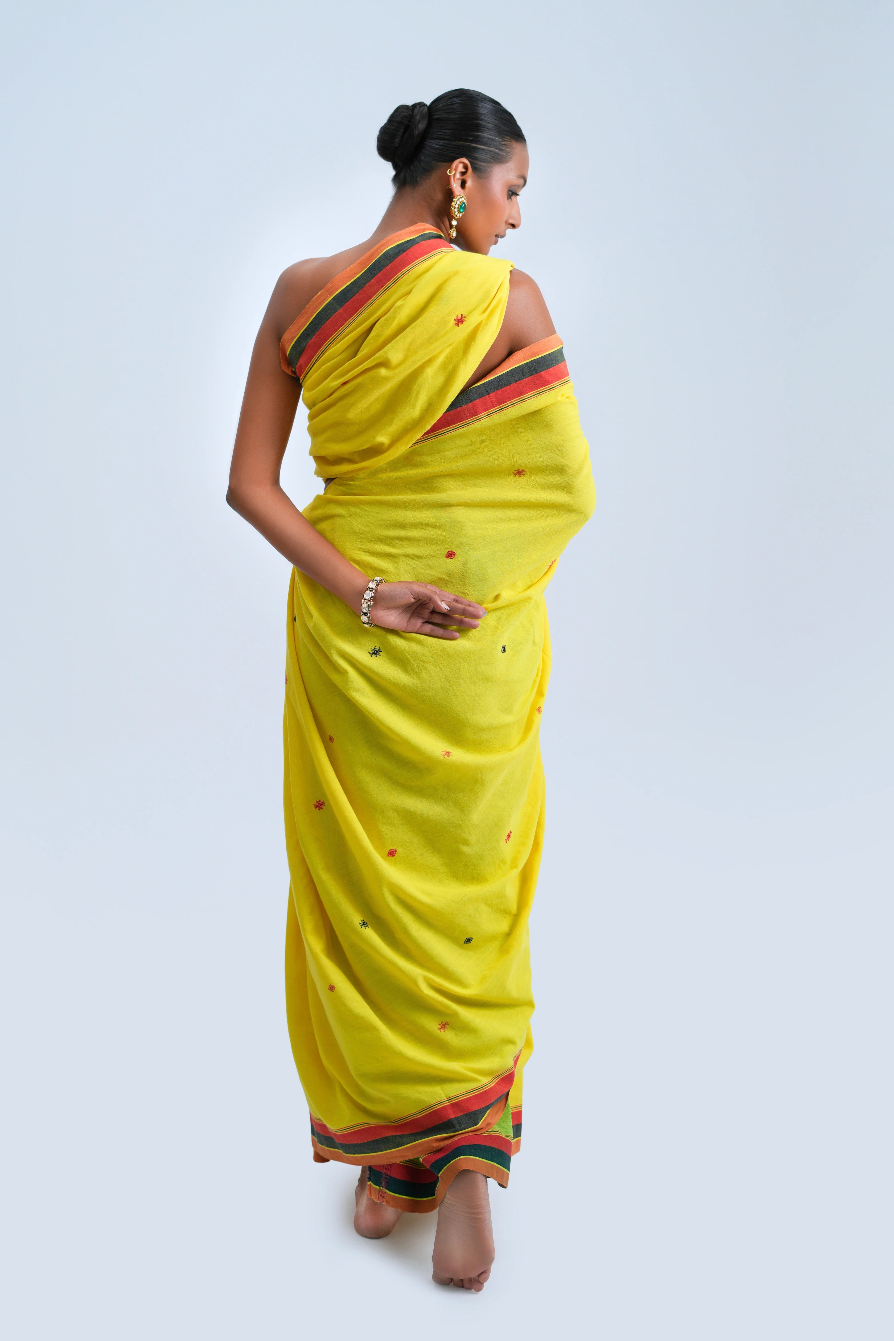 Rear full-length view of a model showcasing the complete drape and border alignment of the yellow Kala cotton saree
