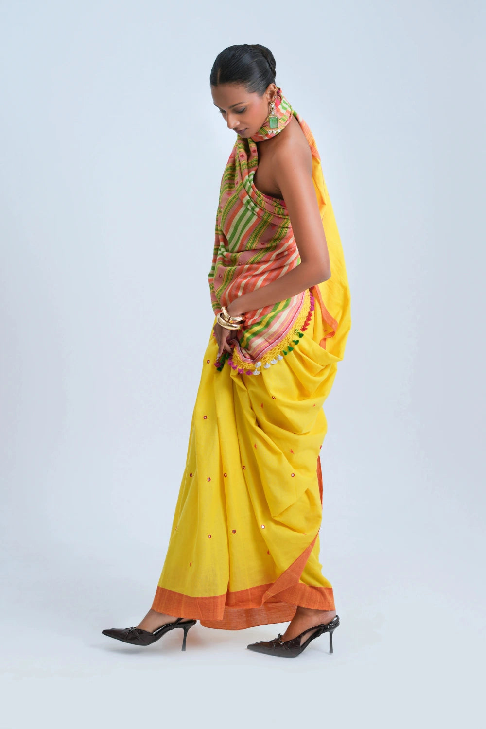 Standing front view showcasing the radiant sunshine yellow body, woven buti motifs, and elegant pleat alignment of the Bhujodi saree