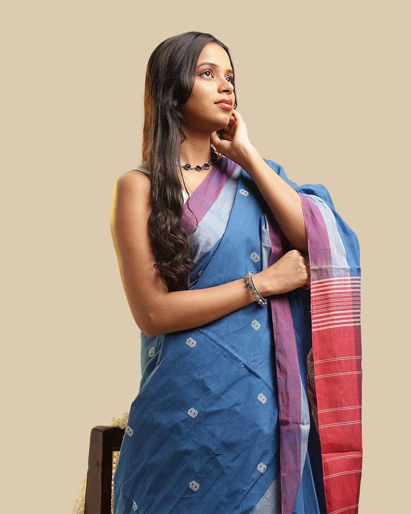 Side-profile studio view highlighting the shoulder pleats, soft orchid border, and overall drape of the twilight blue cotton saree
