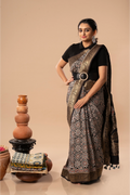 Full-length studio view of a model wearing the black United Tapestry Ajrakh Dola silk saree with golden border, animal motifs, and natural block-printed details
