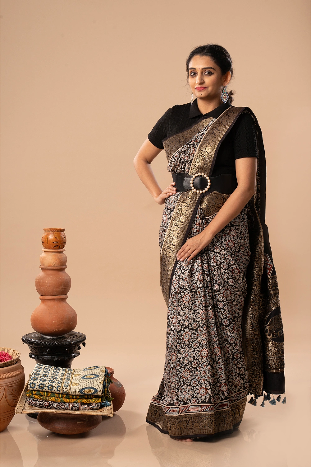 Full-length studio view of a model wearing the black United Tapestry Ajrakh Dola silk saree with golden border, animal motifs, and natural block-printed details