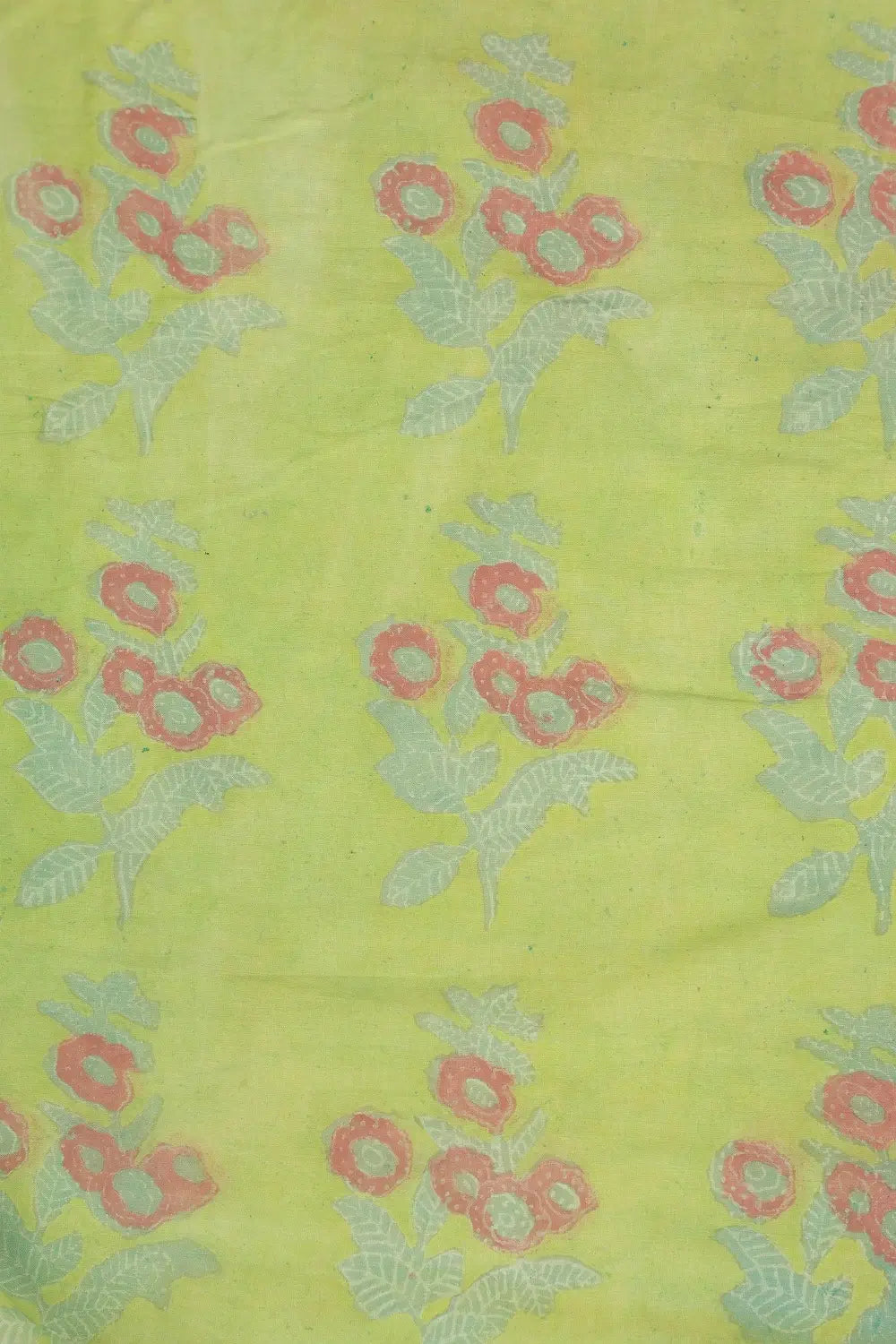 Close-up view of the lime green cotton fabric highlighting the traditional hand-block printed madder red floral motifs