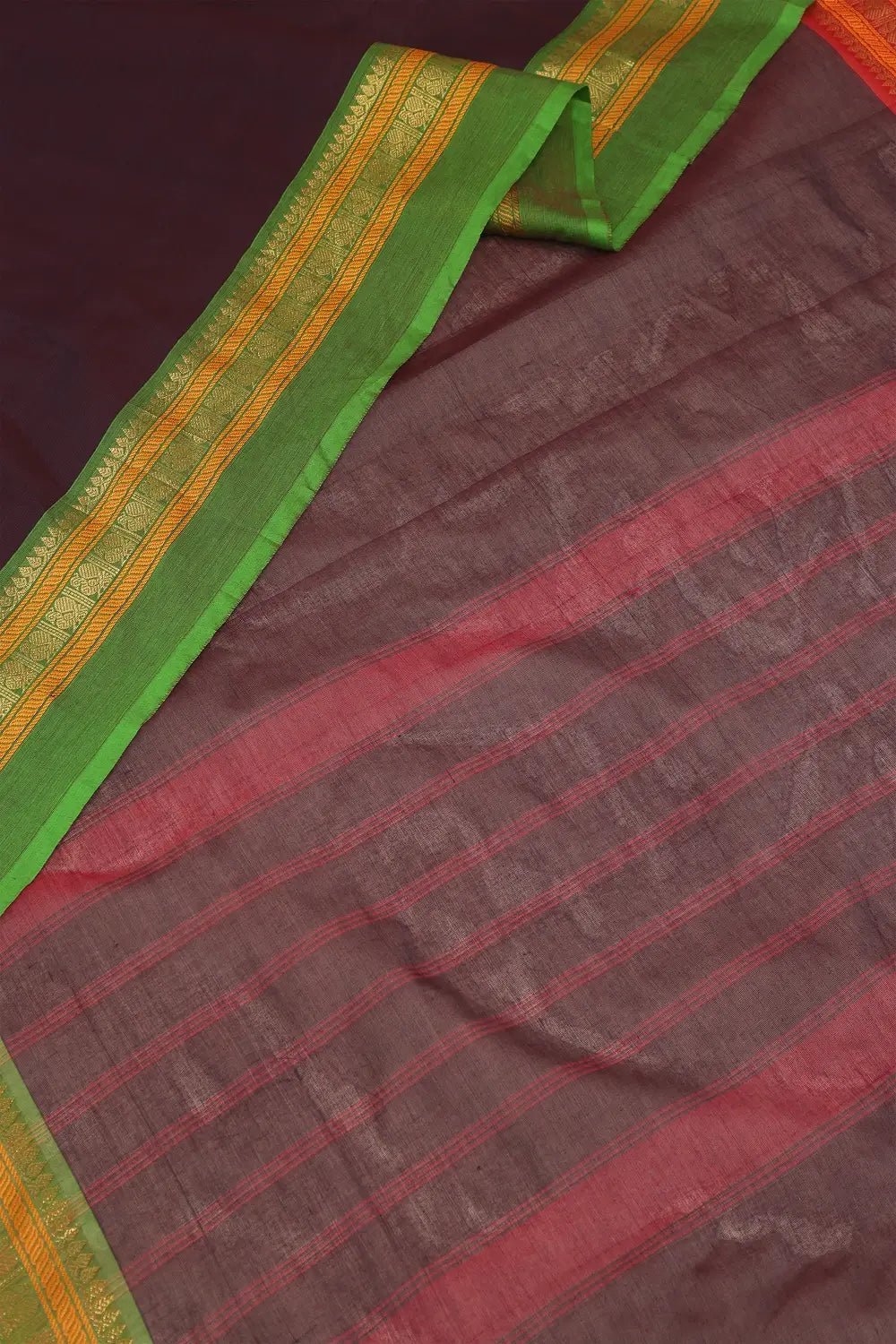 Detailed view of the traditional green and gold border work on the wine cotton saree